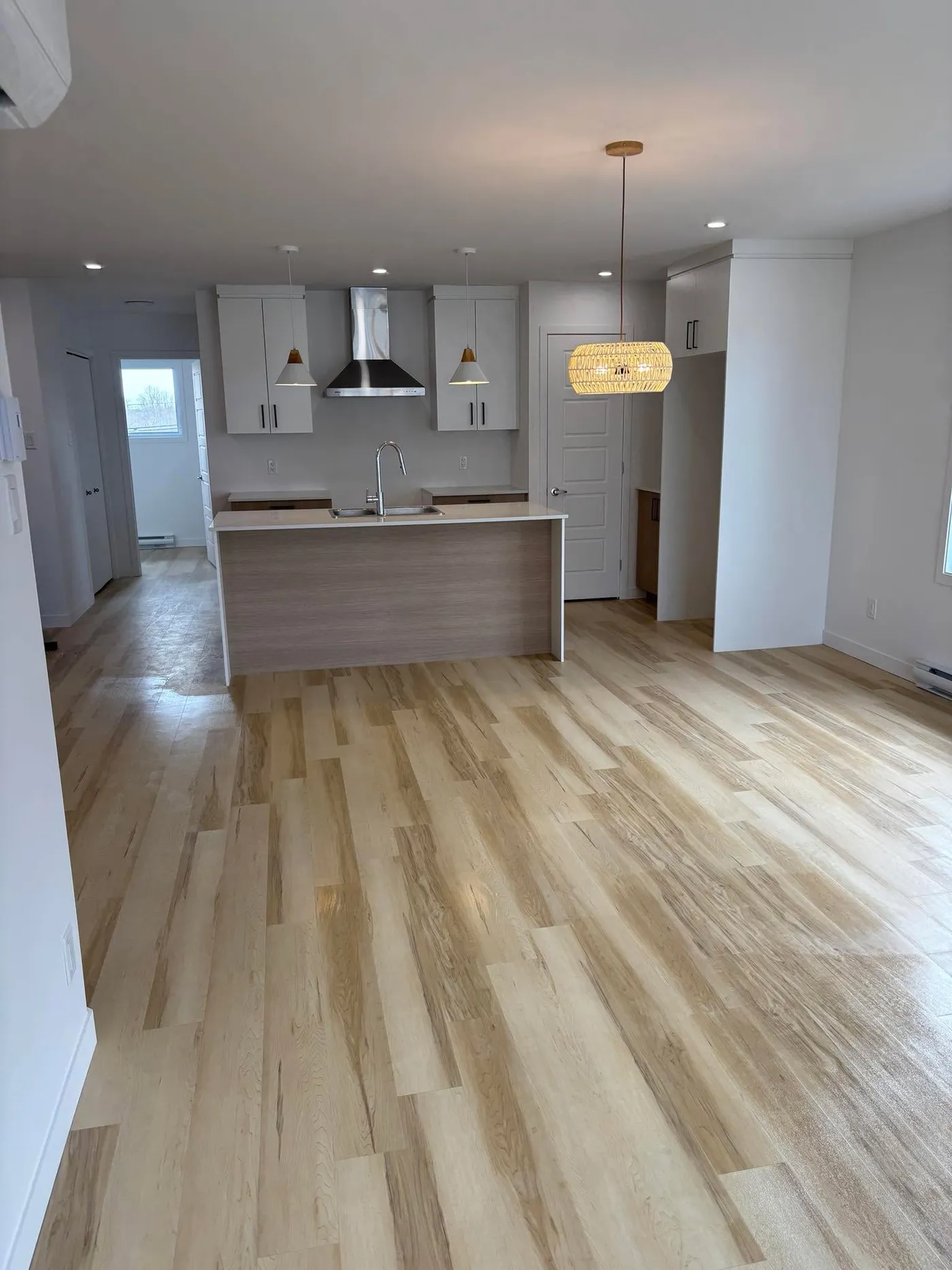 Après — Aire ouverte nettoyée après la construction : planchers de bois et fenêtres impeccables, prête à emménager